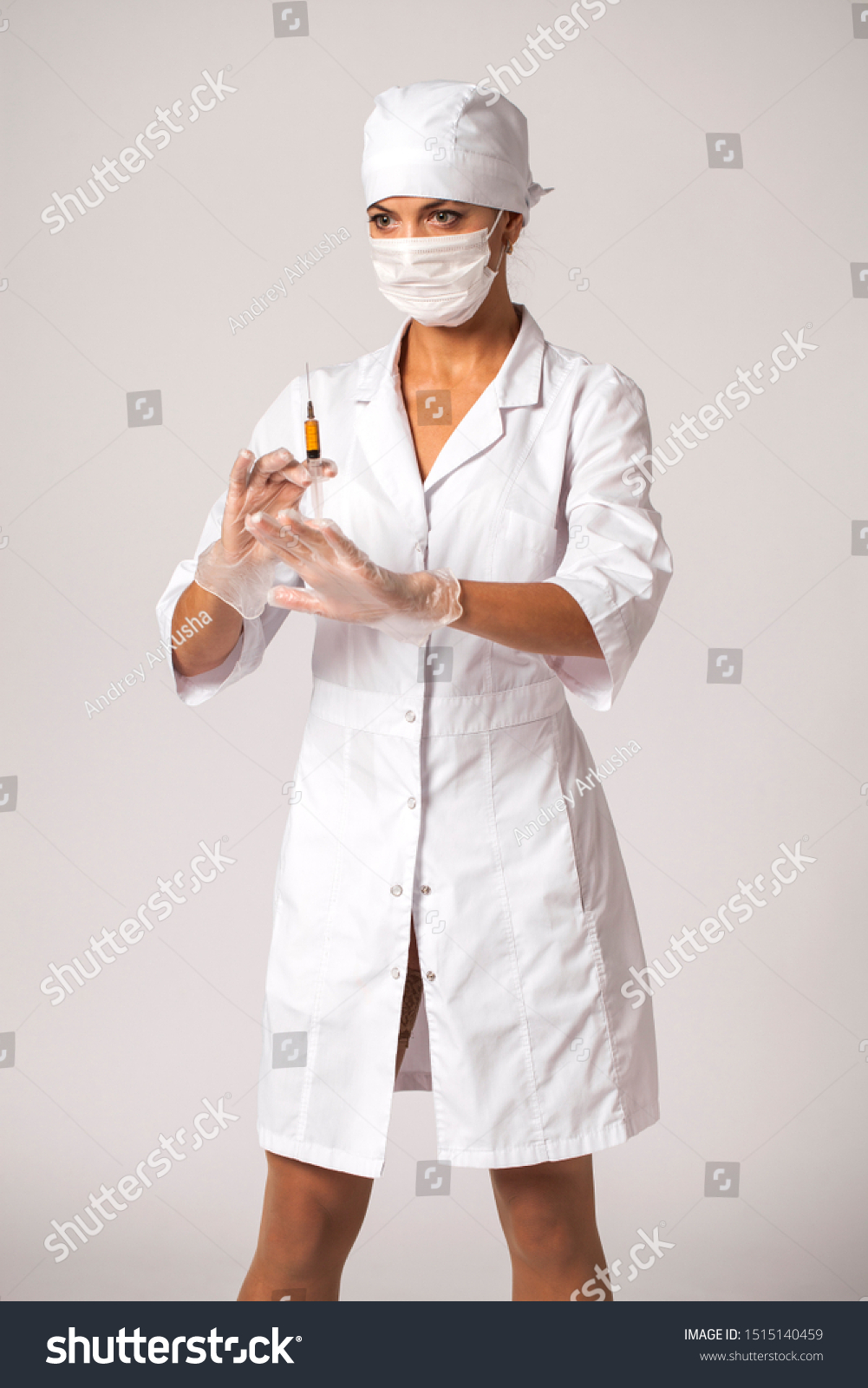 The doctor in a white coat holds a syringe in his hands