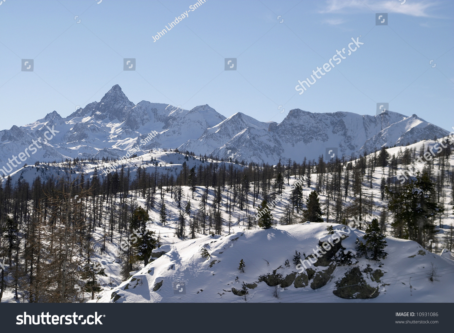 The Jagged Peaks Of The Alps Form A Backdrop To A Snow Covered Hillside ...