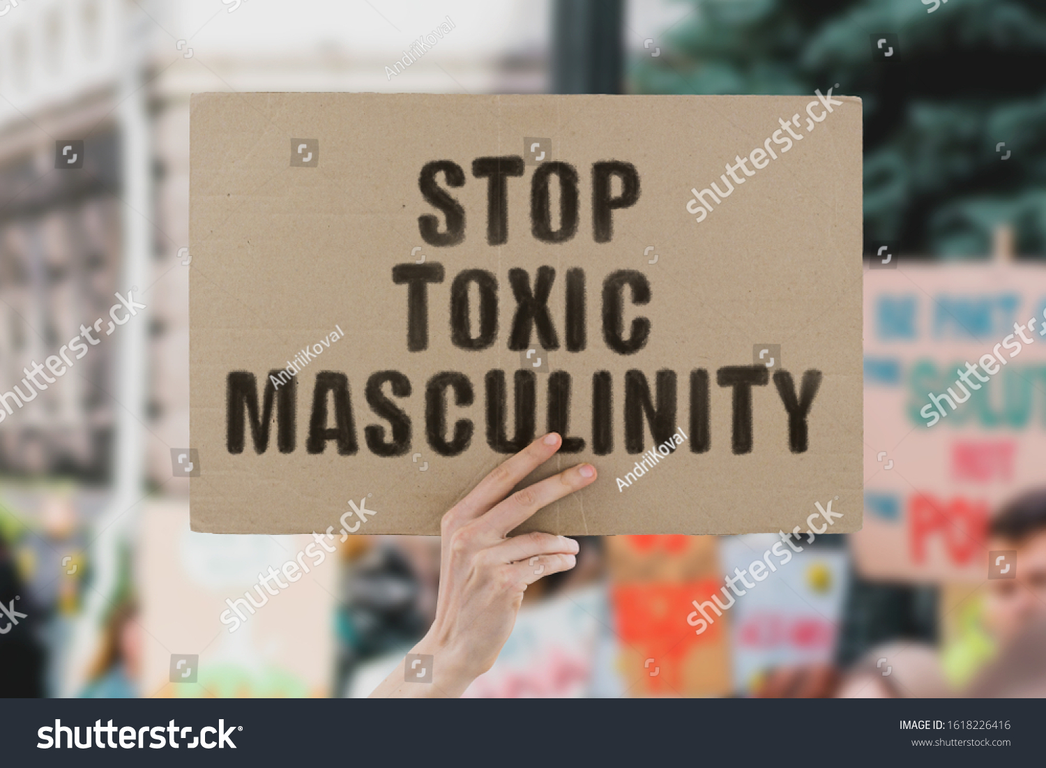 The phrase " Stop toxic masculinity " on a banner in men's hand. Human holds a cardboard with an inscription. Male abuse. Homophobia. Problem. Real man. Respect. Social issues. Equality. Justice