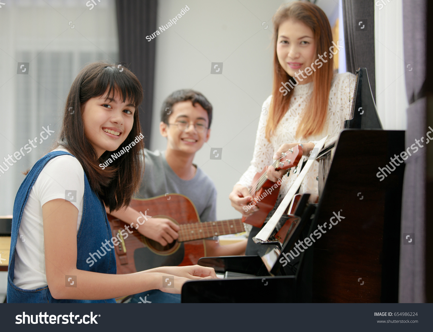 Three people Asian family, mother son and daughter playing music together. Piano, guitar Three People Asian Family Mother Son Stock Photo (Edit Now ...