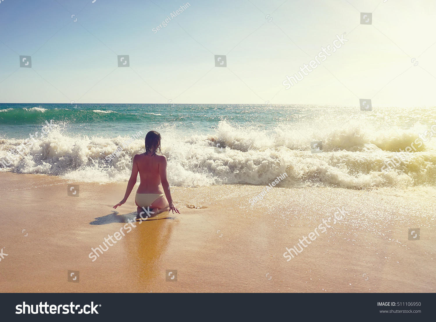 Topless Woman Sitting In Surf On Beautiful Beach At Albufeira Portugal At Sunset Travel