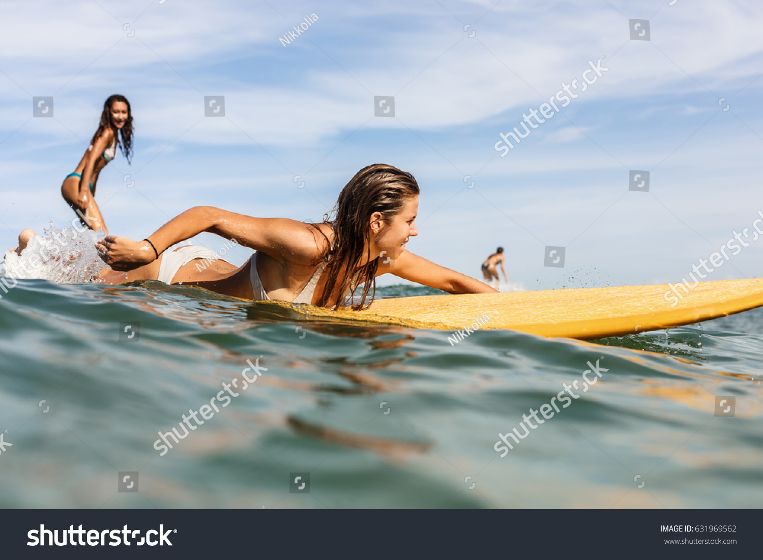 海の日の出や日没の日の出の長いサーフボードの上に 美しいサーフィンガール2人 女は友達のへらをする間に 良い波に乗る 現代の活躍的なスポーツライフスタイルと夏休み の写真素材 今すぐ編集