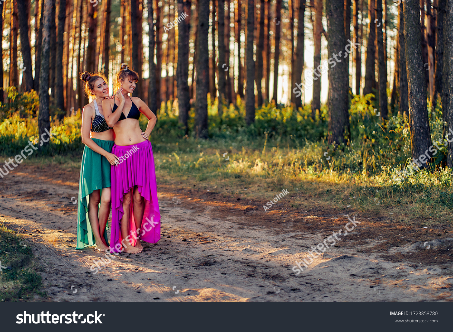 https://image.shutterstock.com/z/stock-photo-two-girls-in-bathing-suits-and-long-dresses-in-the-forest-at-sunset-1723858780.jpg