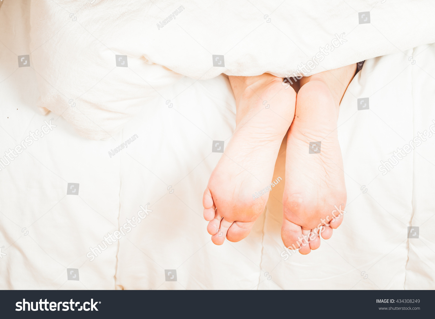 Under The Covers With Feet Showing In A Bed Morning Sunli