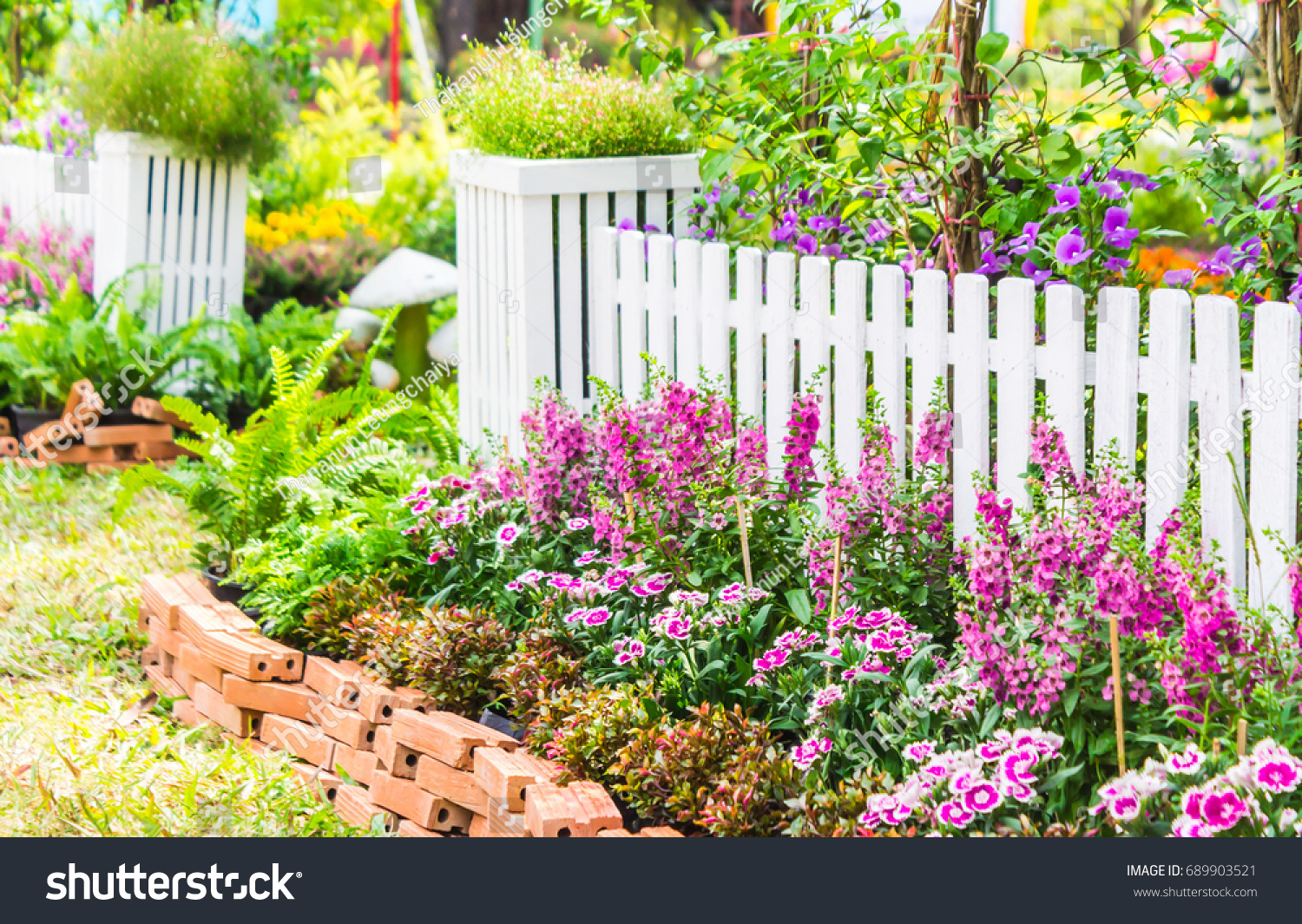 white picket fence surrounded by flowers stock photo (edit now