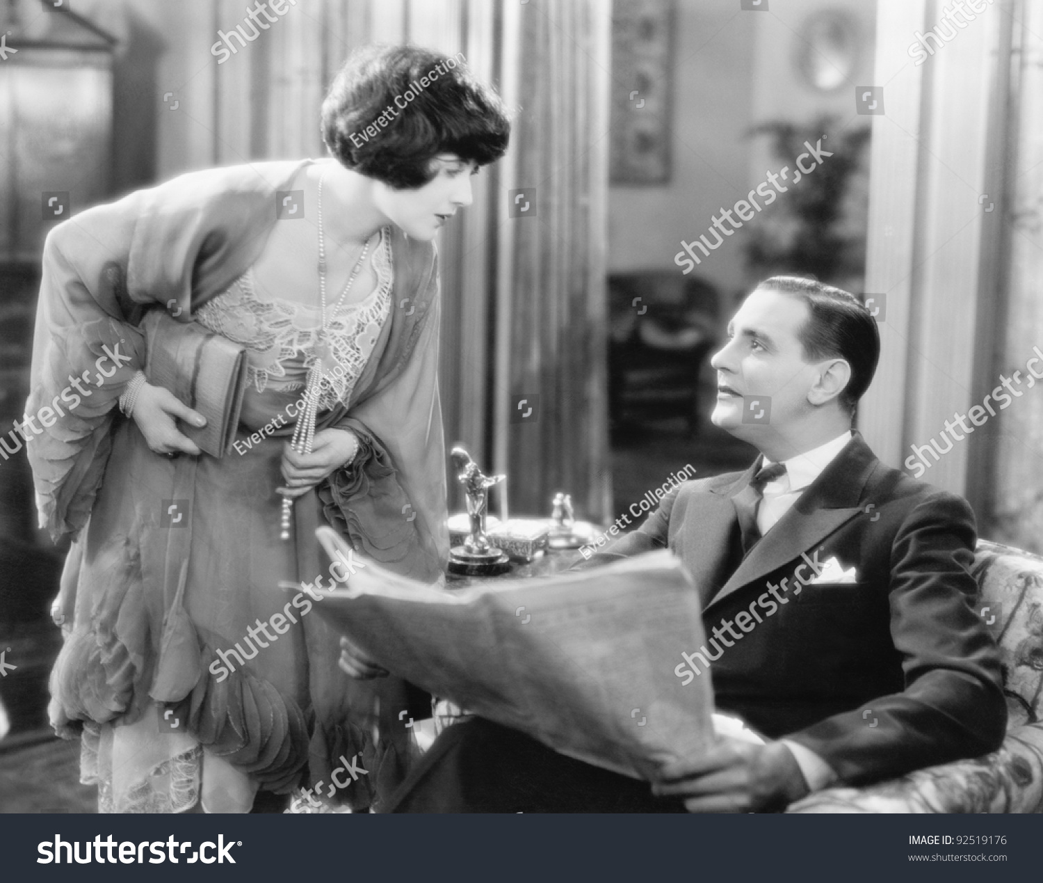 Woman Bending Over To Talk To A Man Holding A Newspaper Stock Photo ...