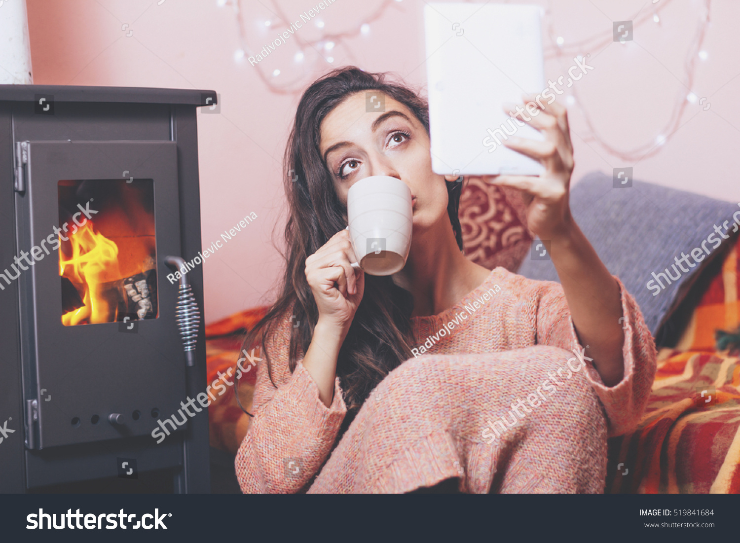 Woman Drinking Cup Of Coffee Relaxing At Fireplace,Looking At Tablet ...