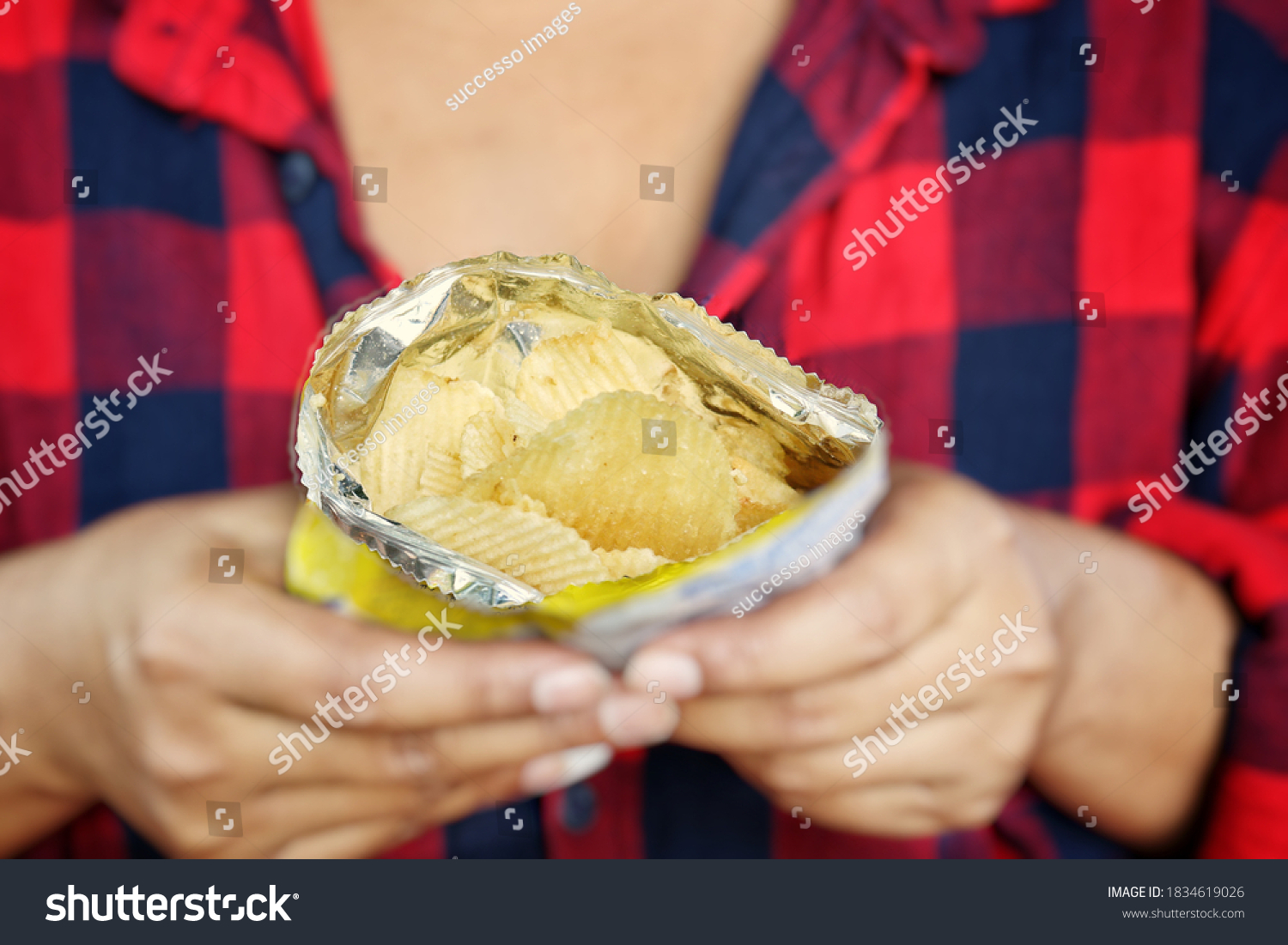 woman-eating-potato-chips-on-hand-stock-photo-1834619026-shutterstock