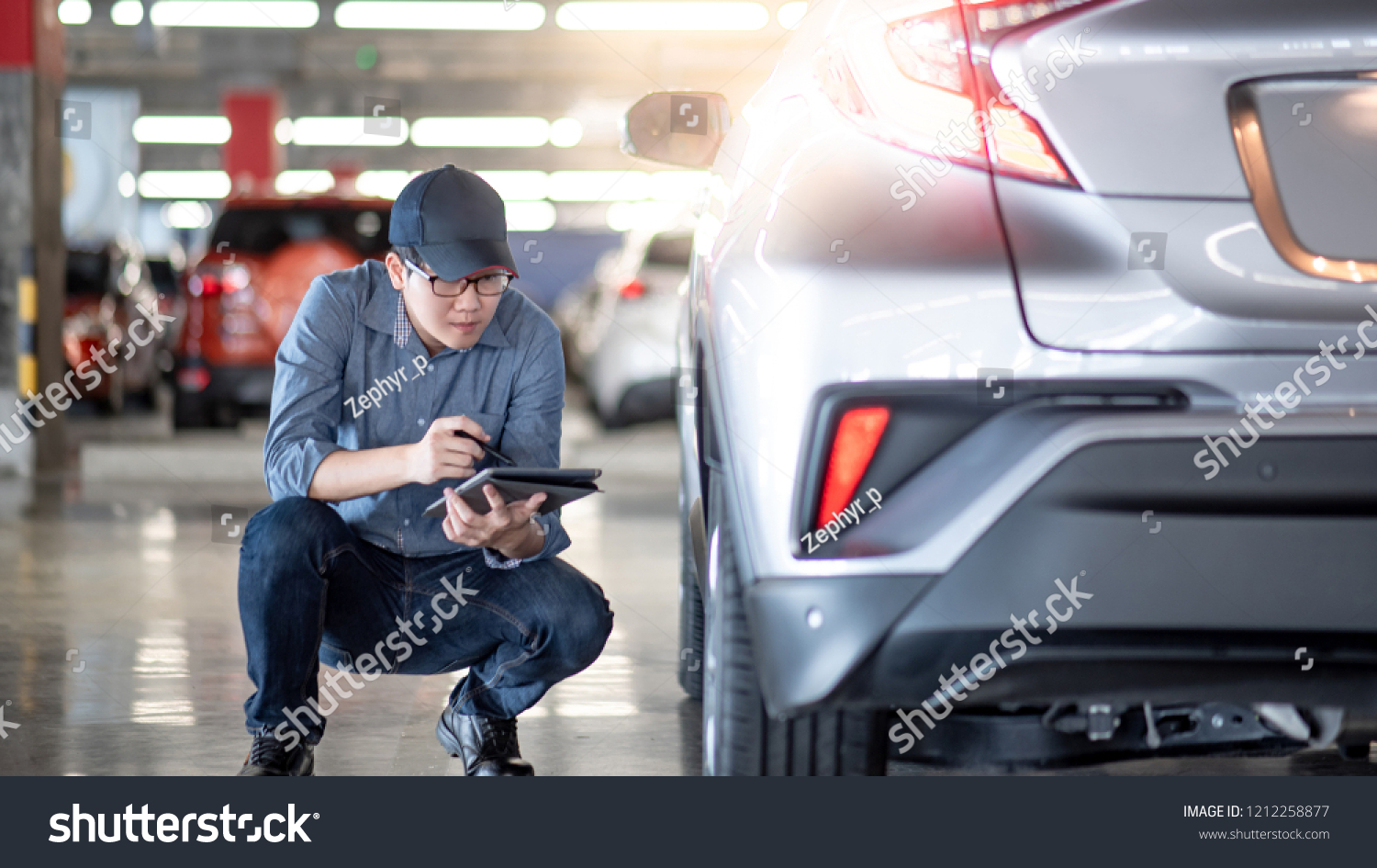 自動車の修理工場にデジタルタブレットチェック車の車輪を入れたアジアの若い自動車整備士 自動車産業で働く機械整備士 自動車の修理 修理のコンセプト の写真素材 今すぐ編集