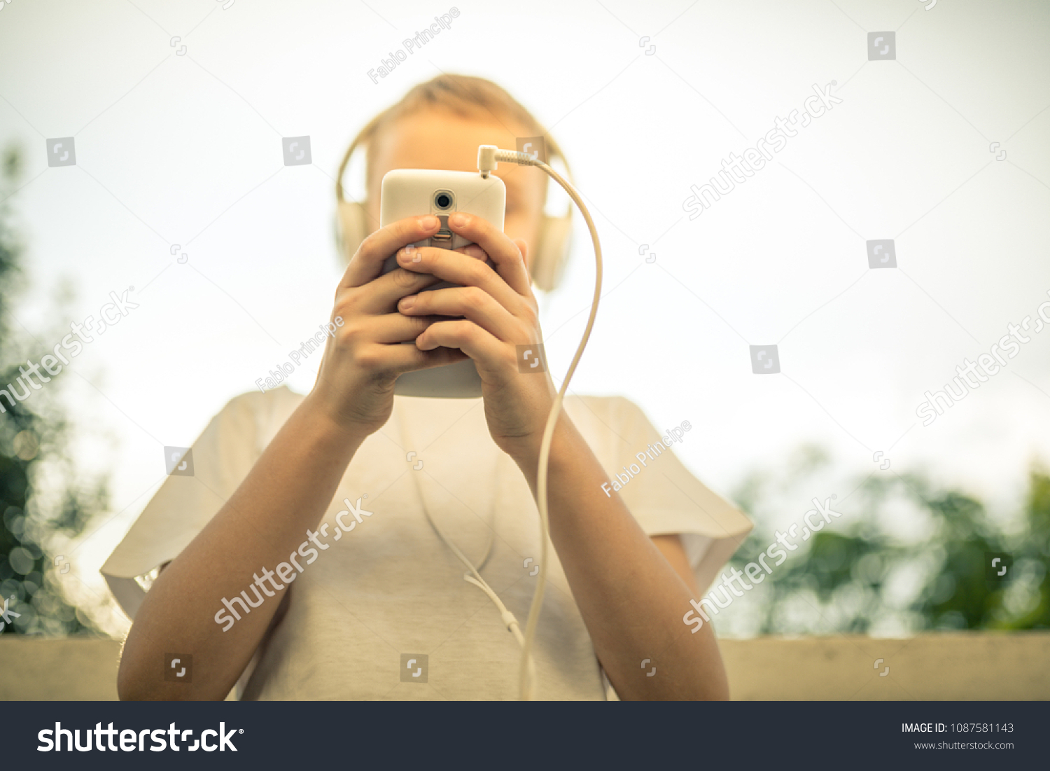 Young boy alone listening music with smartphone pre teen alone play with phone in hand