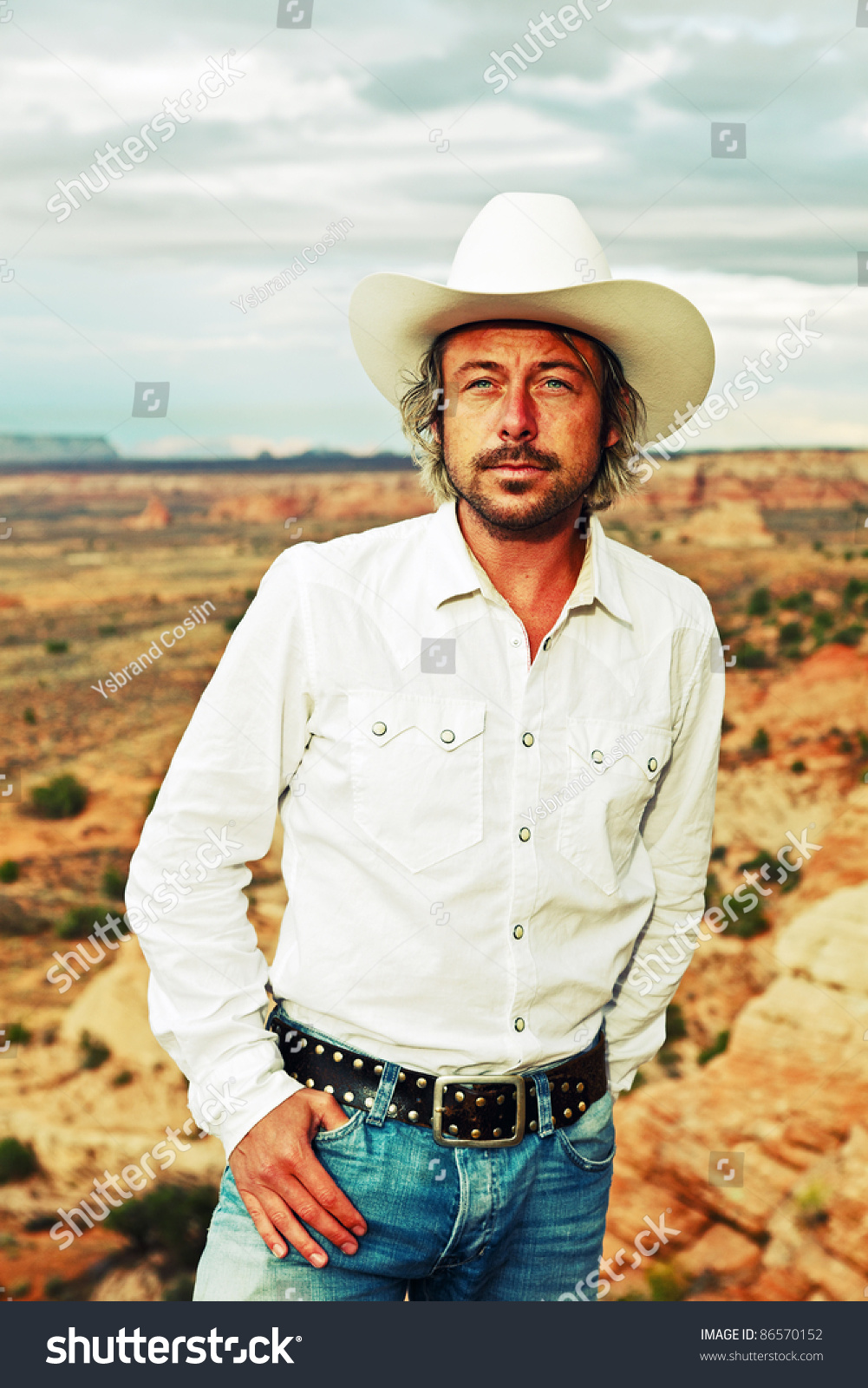 Young Cowboy With White Hat And Shirt Standing In Desert Landscape With ...