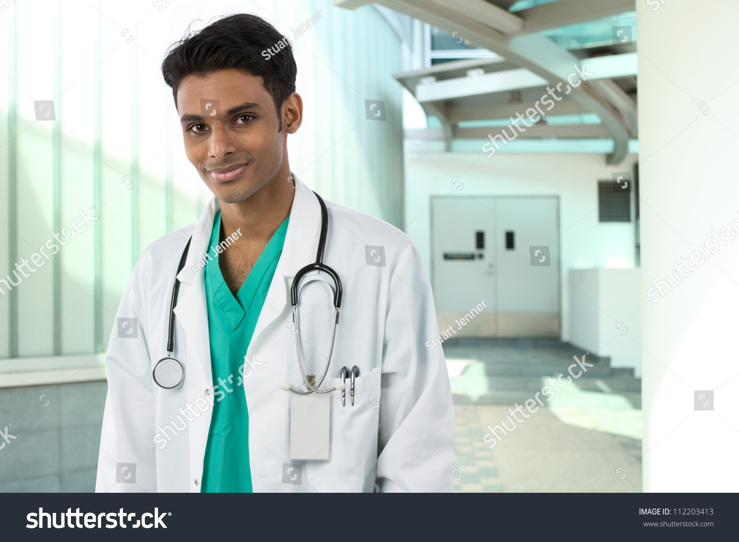 Young Male Indian Doctor Wearing A White Coat And Stethoscope. Standing ...