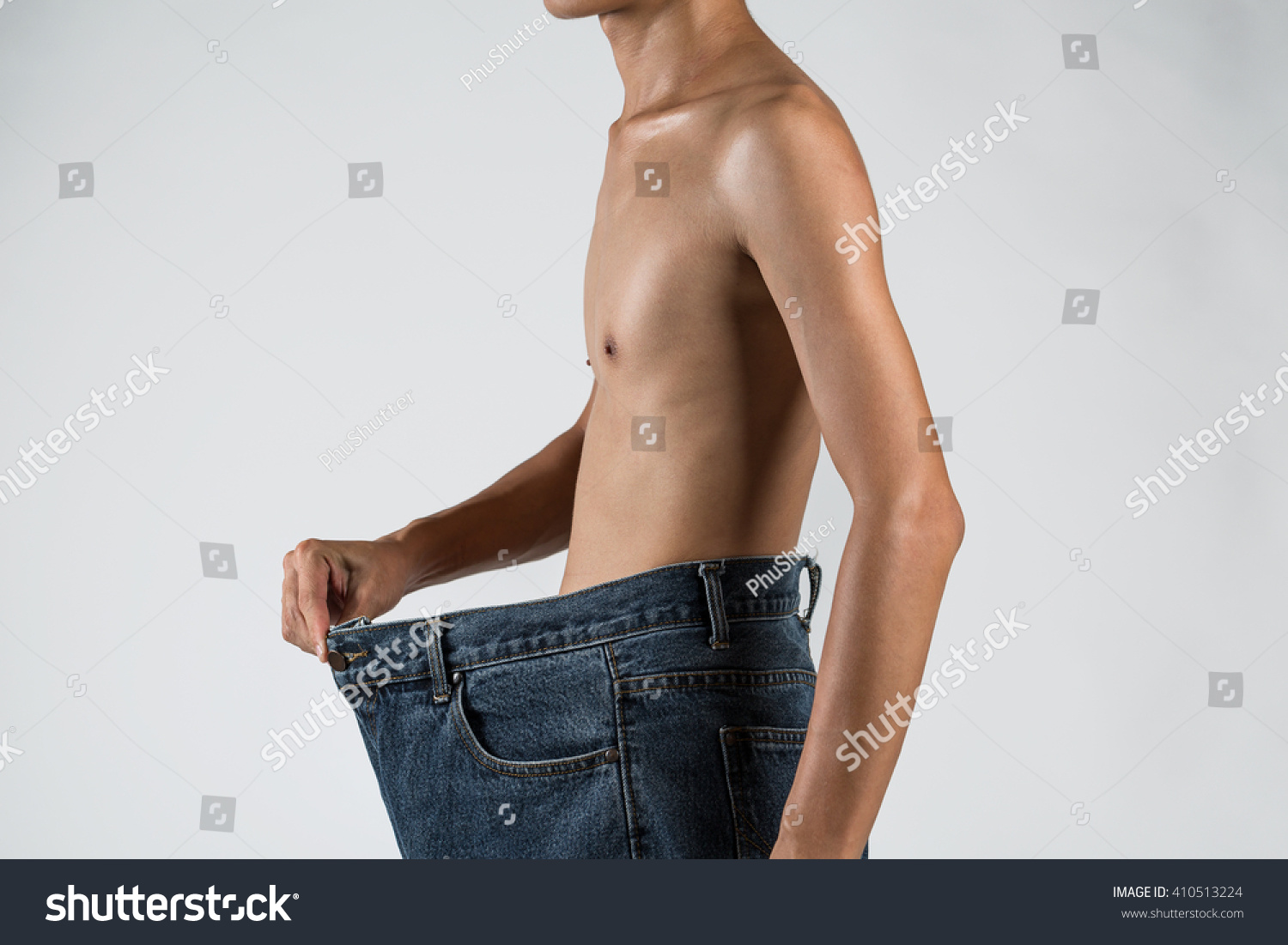 Young Man Showing His Lost Weight By Putting On An Old Jeans Close Up