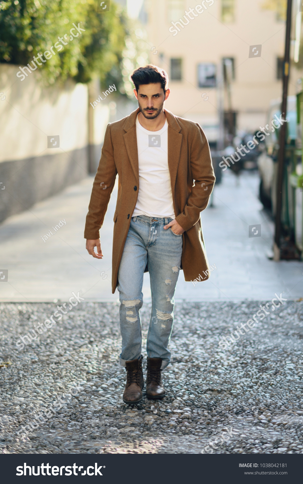 Young man wearing winter clothes in the street. Young bearded guy with modern hairstyle with