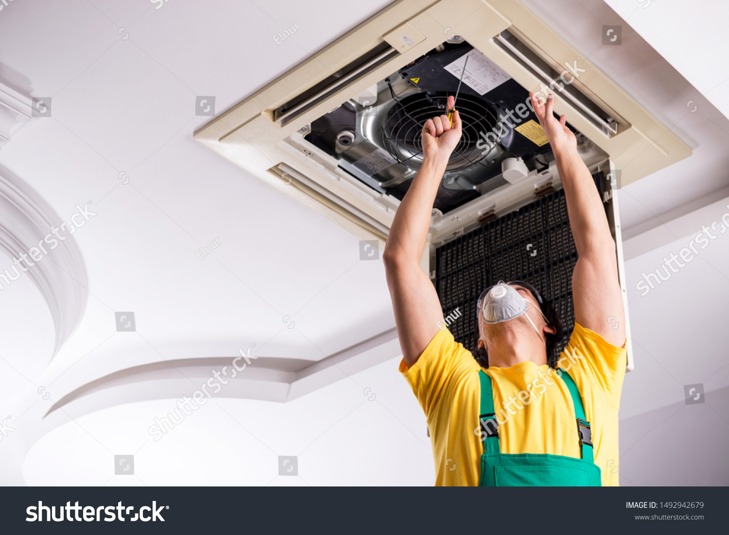 Young Repairman Repairing Ceiling Air Conditioning Stock