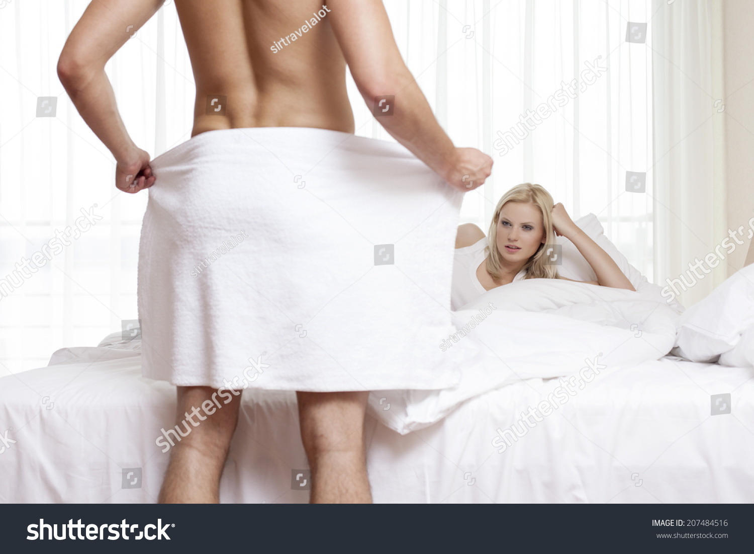 Young Woman Staring At Naked Man Holding Towel In Bedroom 